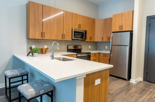 A u-shaped kitchen with ample cabinet space, stainless steel appliances, hardwood flooring, and a large breakfast bar.