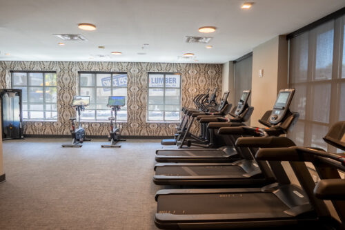 Spacious fitness center with a variety of workout equipment and large windows.