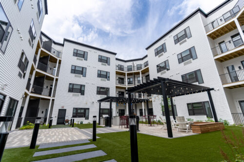 The Hive's courtyard with outdoor seating options, fire pits, grills, and a trellis with string lights.