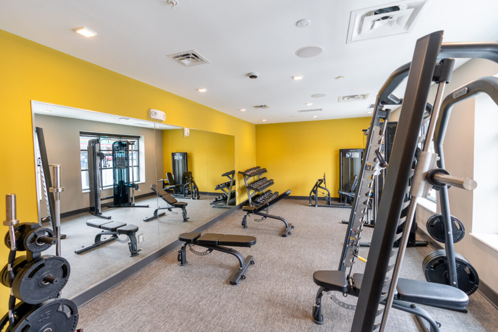 Spacious fitness center with a variety of workout equipment, large mirrors, and windows.